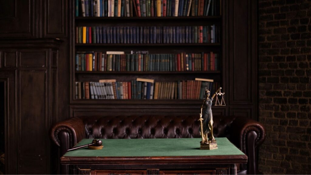 Cabinet avocat avec librairie au fond, bureau en premier plan et une balance de justice